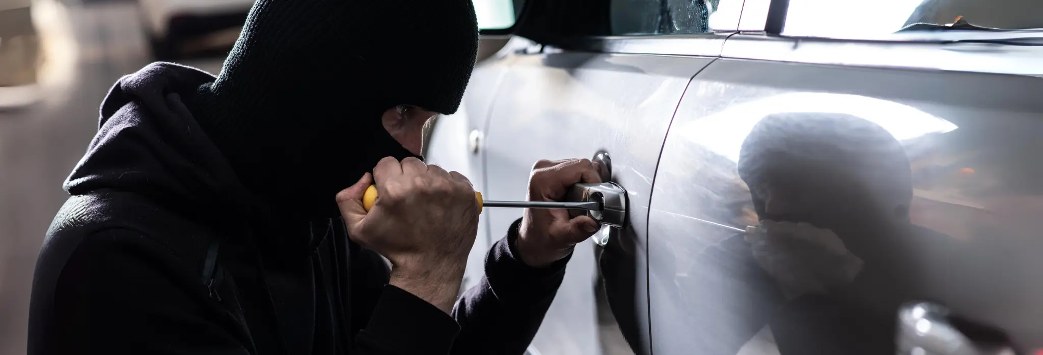 Κλέφτης με μαύρα ρούχα παραβιάζει πόρτα αυτοκινήτου με κατσαβίδι