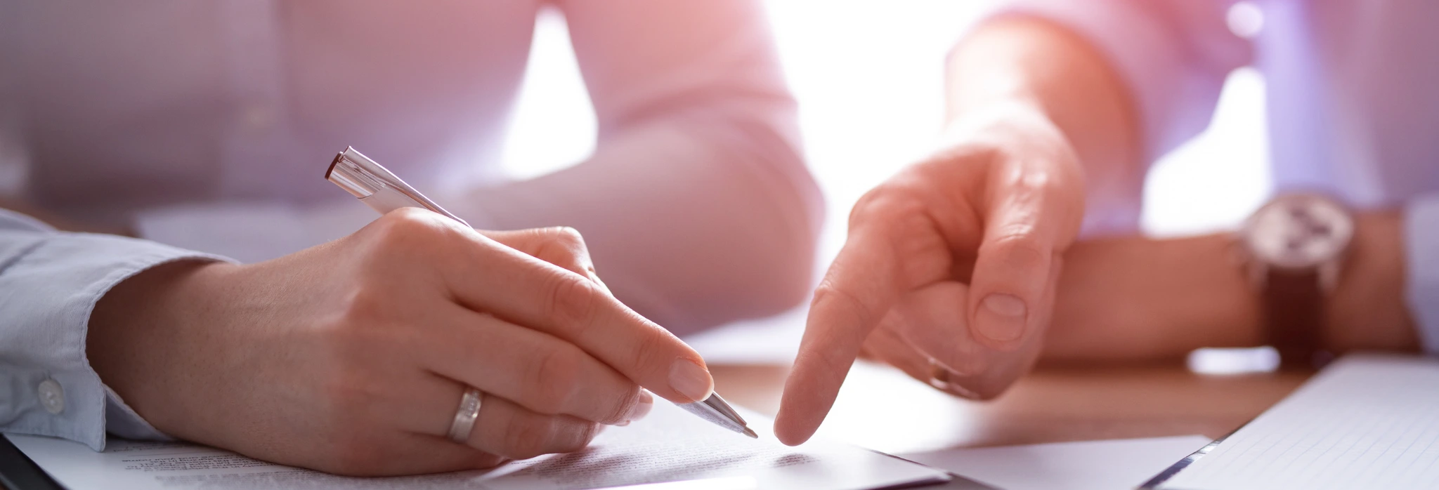 Δύο άτομα εξετάζουν και υπογράφουν ένα συμβόλαιο, με το ένα άτομο να δείχνει ένα συγκεκριμένο σημείο στο έγγραφο.