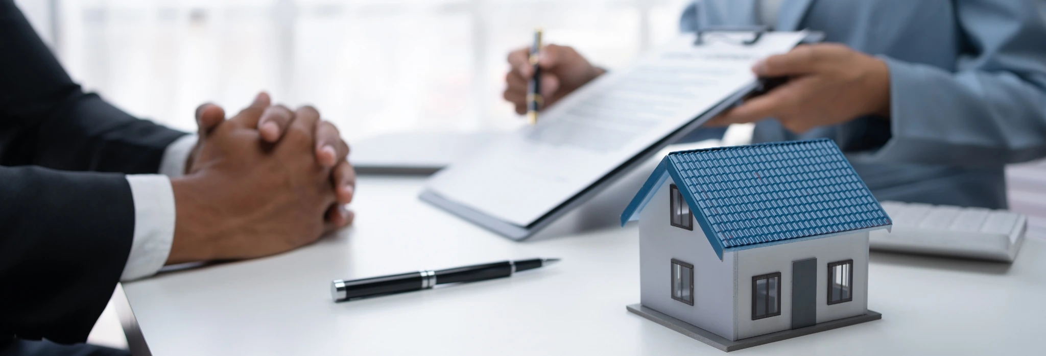 Δύο άνθρωποι σε τραπέζι κοιτάνε συμβόλαιο για στεγαστικό δάνειο.