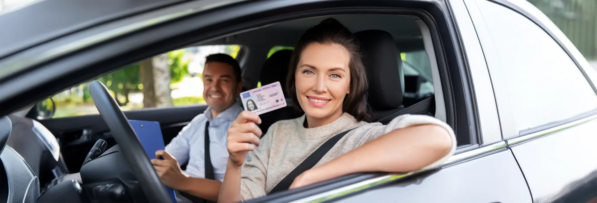 Νέα οδηγός με δίπλωμα οδήγησης στη θέση του οδηγού και ο εξεταστής στη θέση του συνοδηγού.