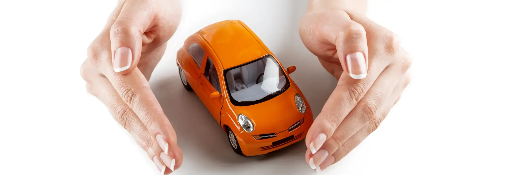 Χέρια γύρω από πορτοκαλί αυτοκινητάκι μινιατούρα.