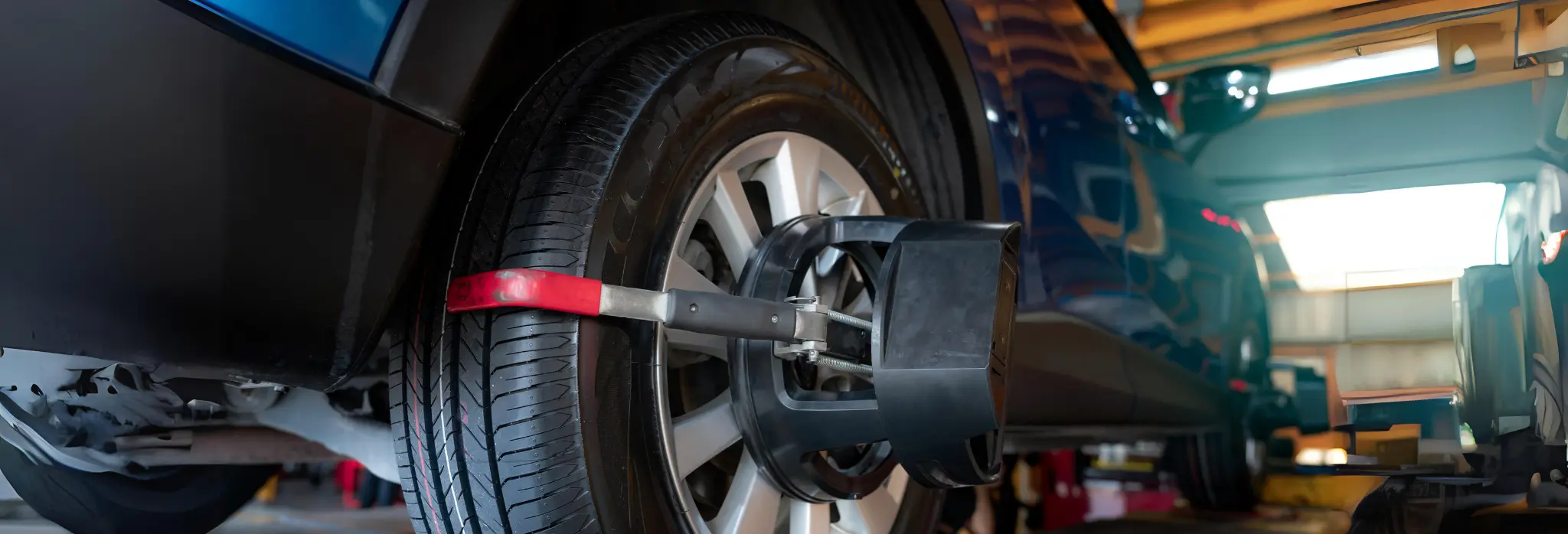 Αυτοκίνητο σε συνεργείο κατά τη διαδικασία ευθυγράμμισης τροχών, με ειδικό εξοπλισμό τοποθετημένο στον τροχό.