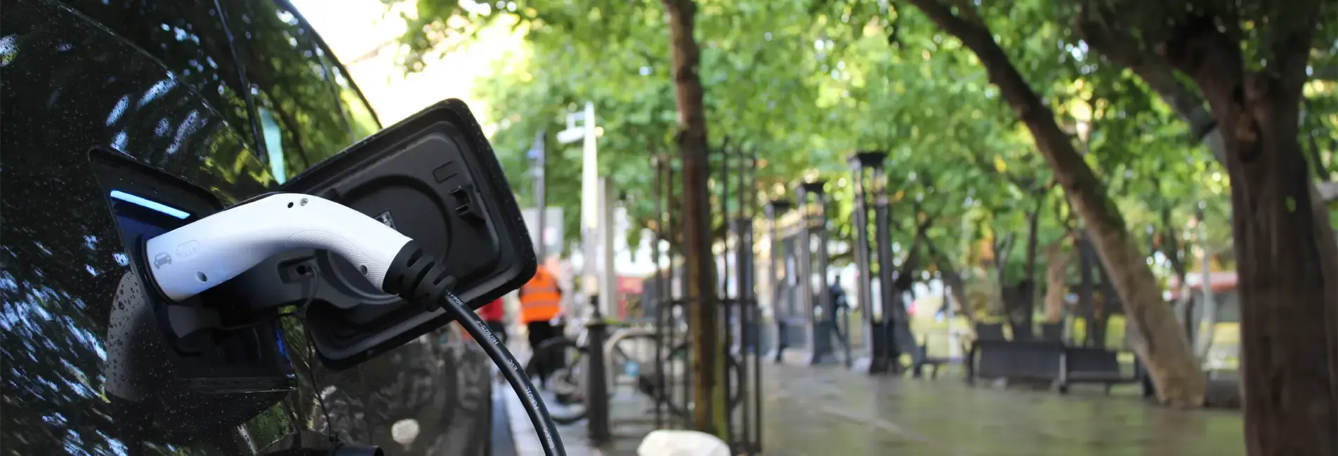 Ηλεκτρικό αυτοκίνητο παρκαρισμένο σε πεζόδρομο με δέντρα.