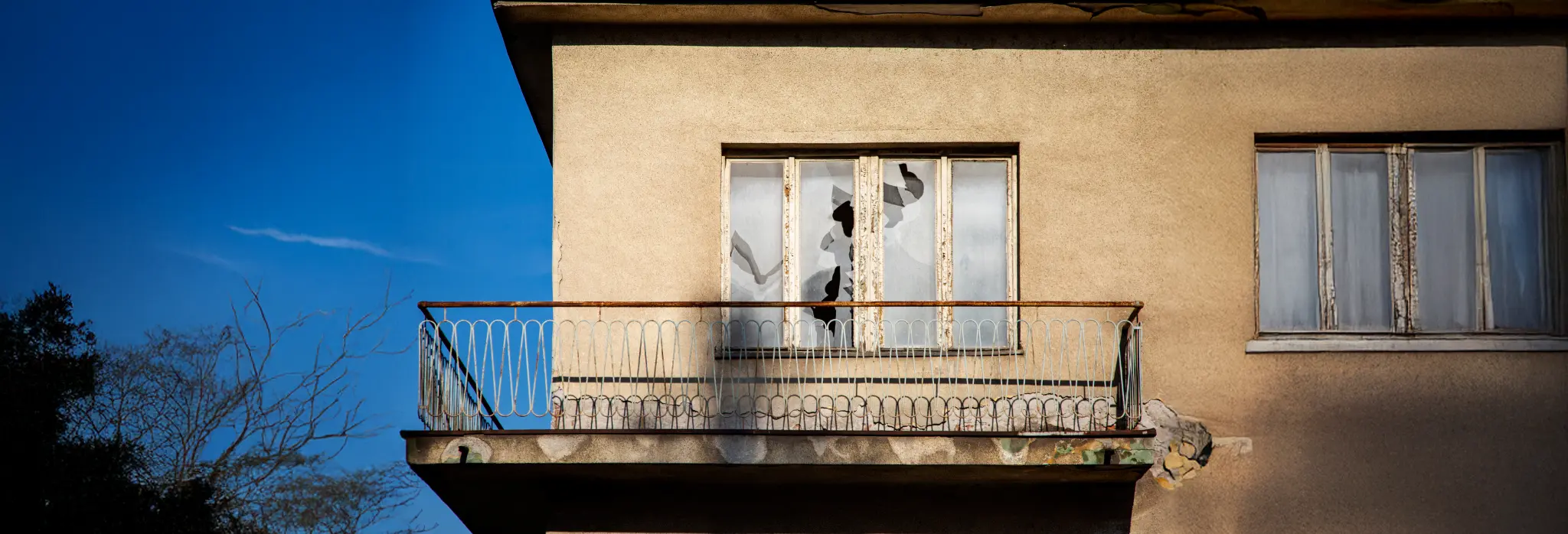 Μπαλκόνι κατοικίας με σπασμένα τζάμια παραθύρων.