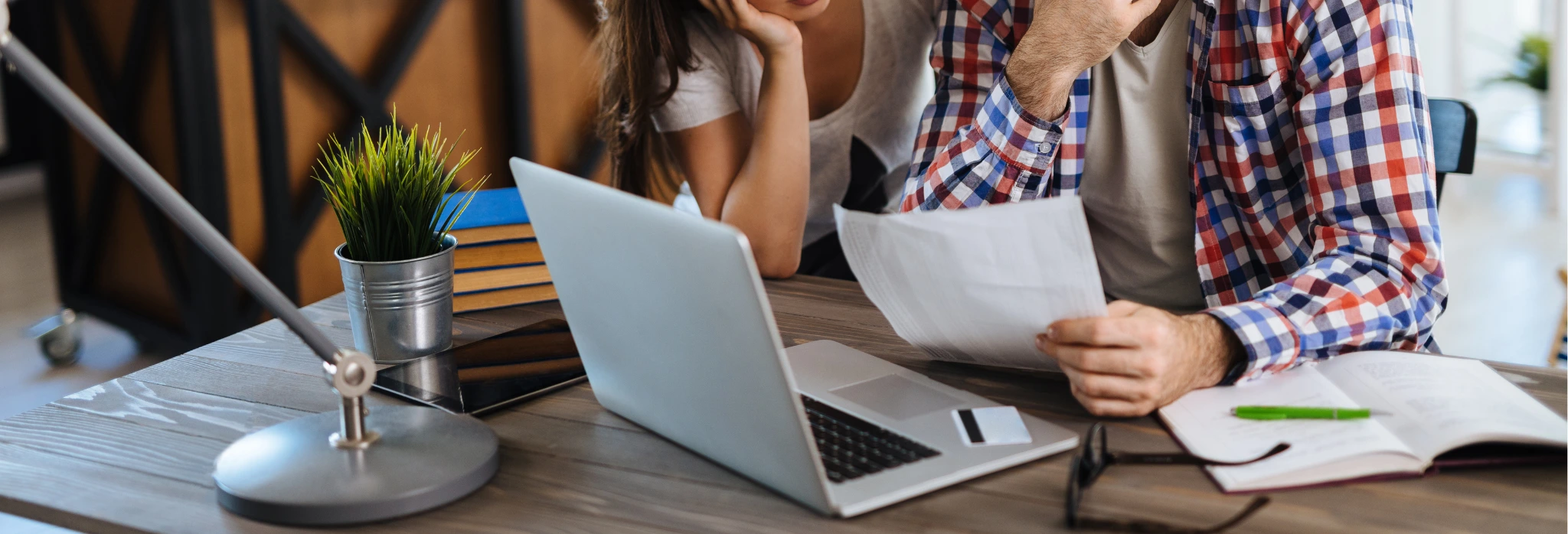 Δύο άτομα κάθονται σε γραφείο μπροστά σε laptop και κοιτάνε τον λογαριασμό.