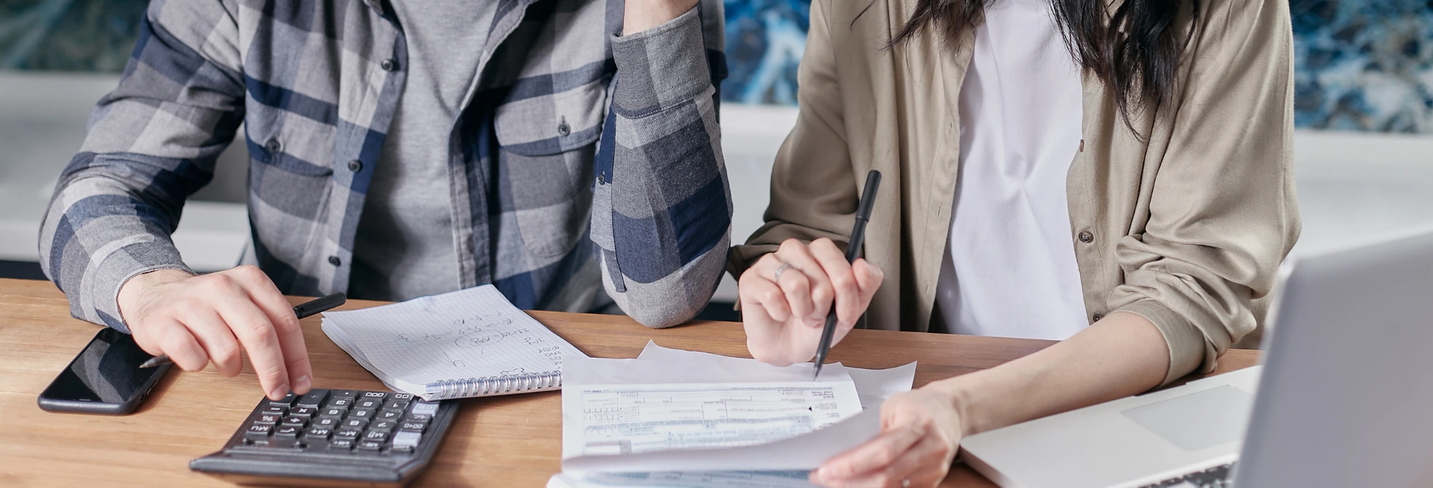 Δύο άνθρωποι με κομπιουτεράκι και λογαριασμό ρεύματος σε γραφείο.