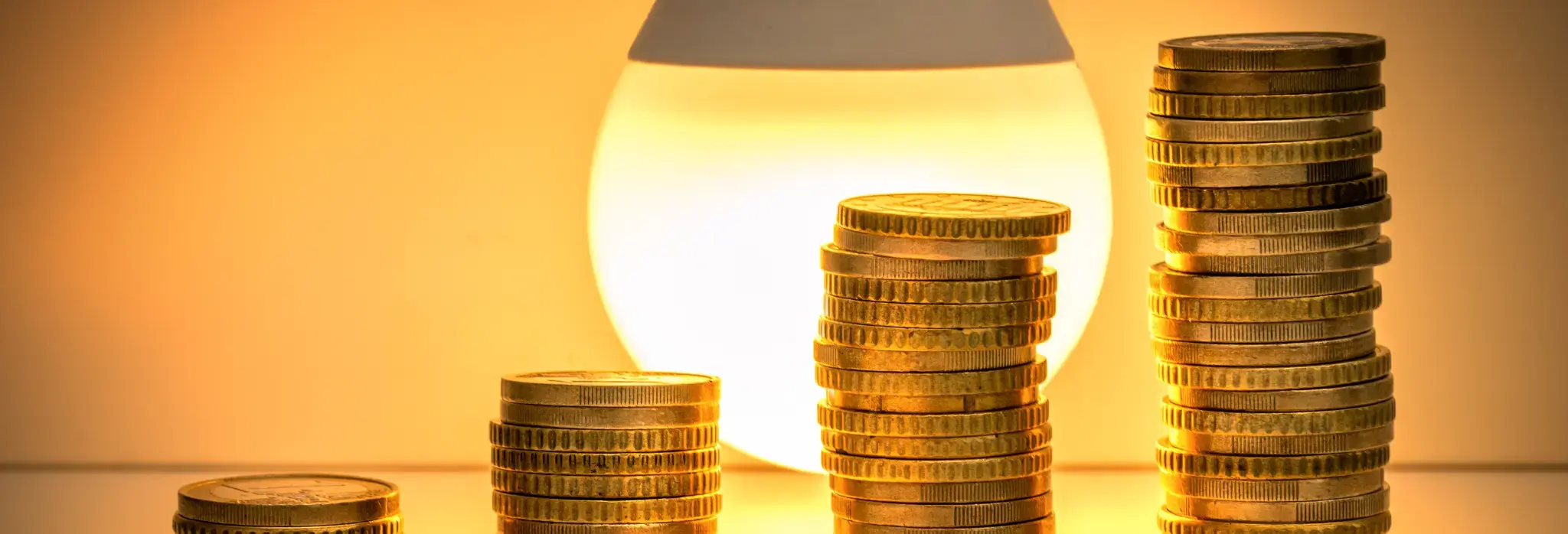 Στοιβαγμένα νομίσματα μπροστά από φωτιστικό.