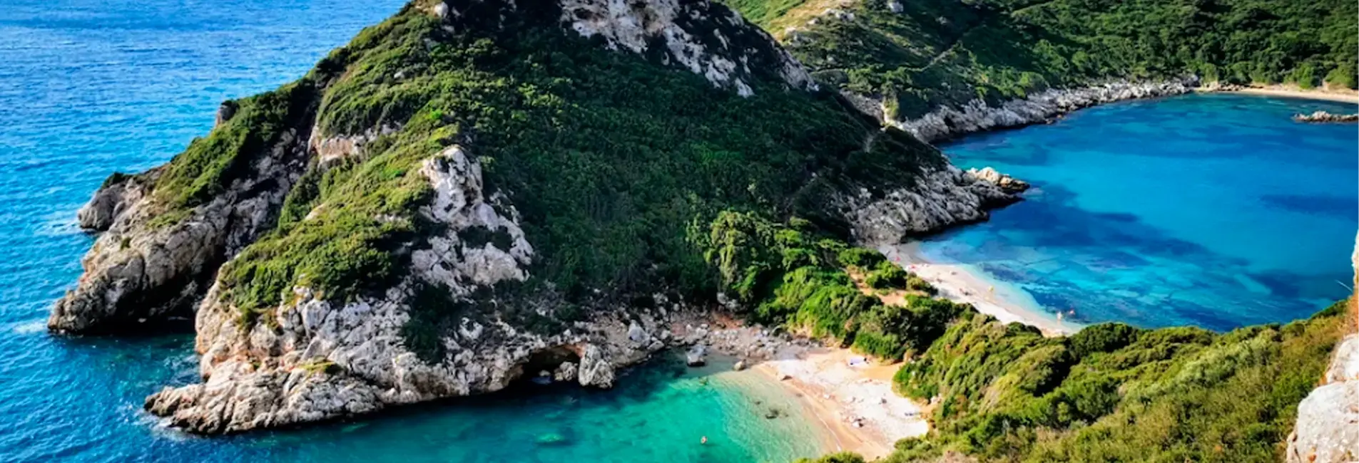 Πράσινη χερσόνησος με βραχώδεις ακτές περιβάλλεται από γαλαζοπράσινα νερά και παραλίες με λουόμενους.