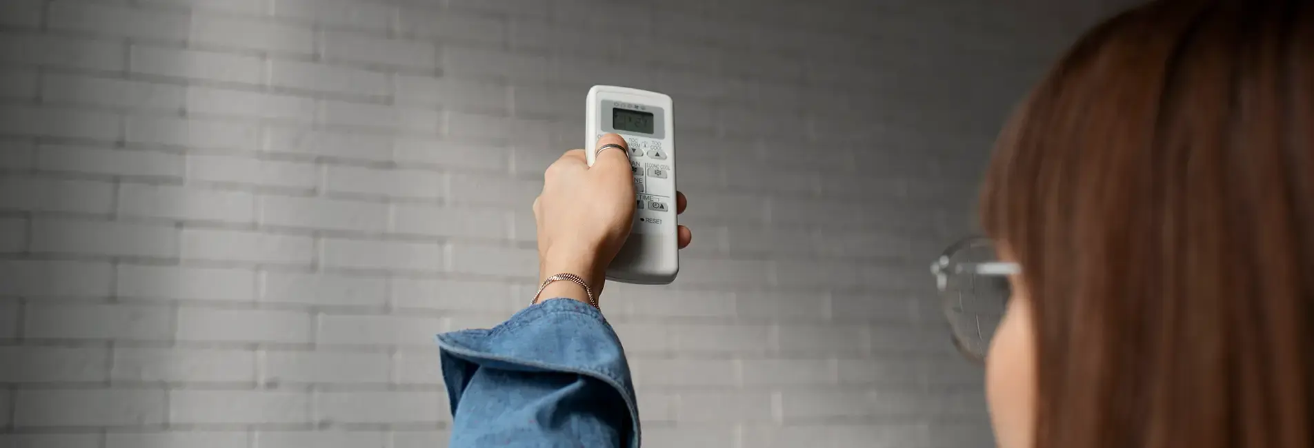 Κοπέλα με τηλεχειρηστήριο ενεργοποιεί κλιματιστικό.