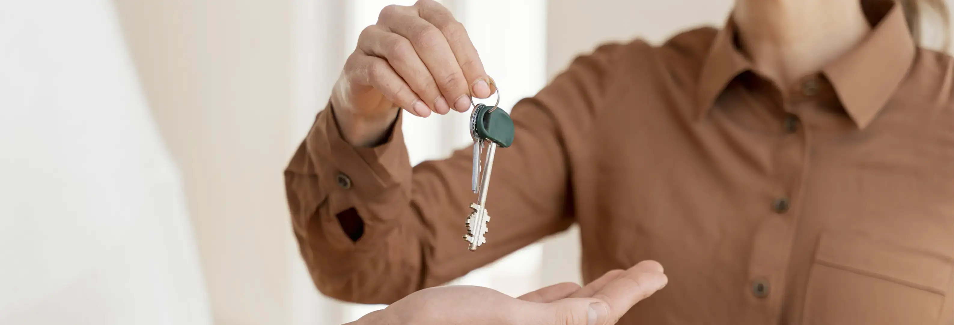 Χέρι που δίνει κλειδί σπιτιού σε άλλο χέρι.