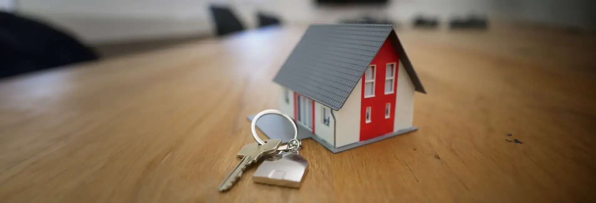Μικρό σπιτάκι και κλειδιά πάνω σε τραπέζι.