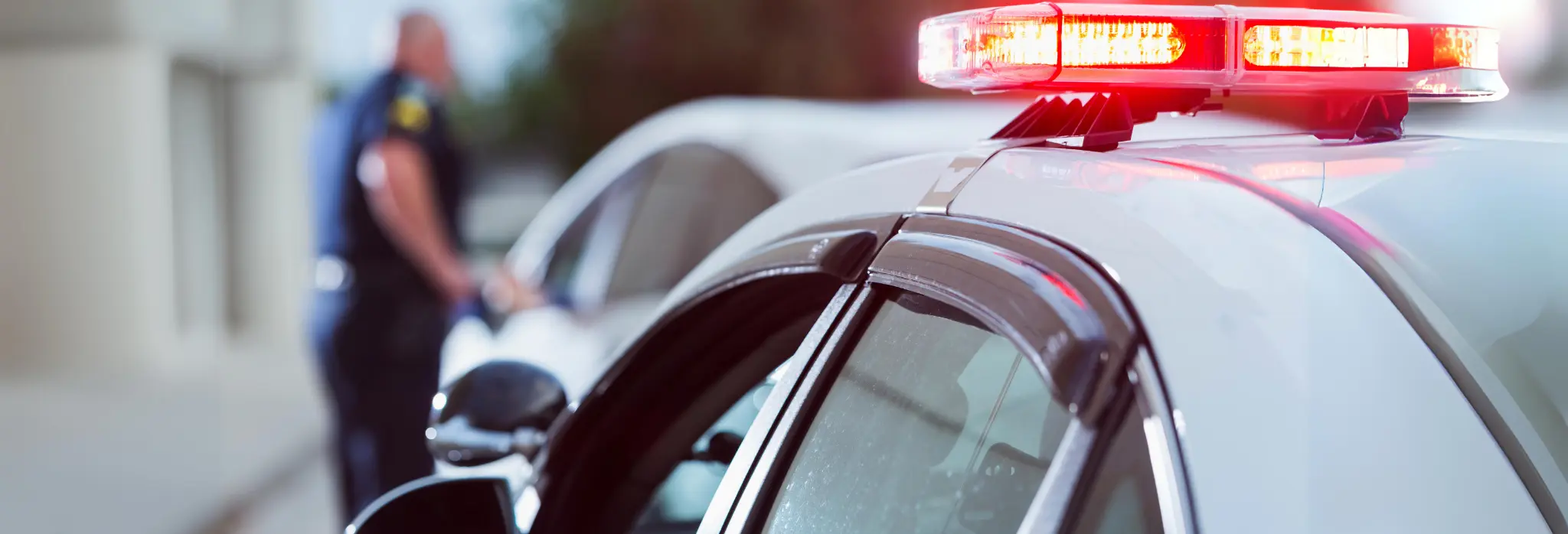 Αστυνομικός κάνει έλεγχο σε όχημα έξω από το περιπολικό.