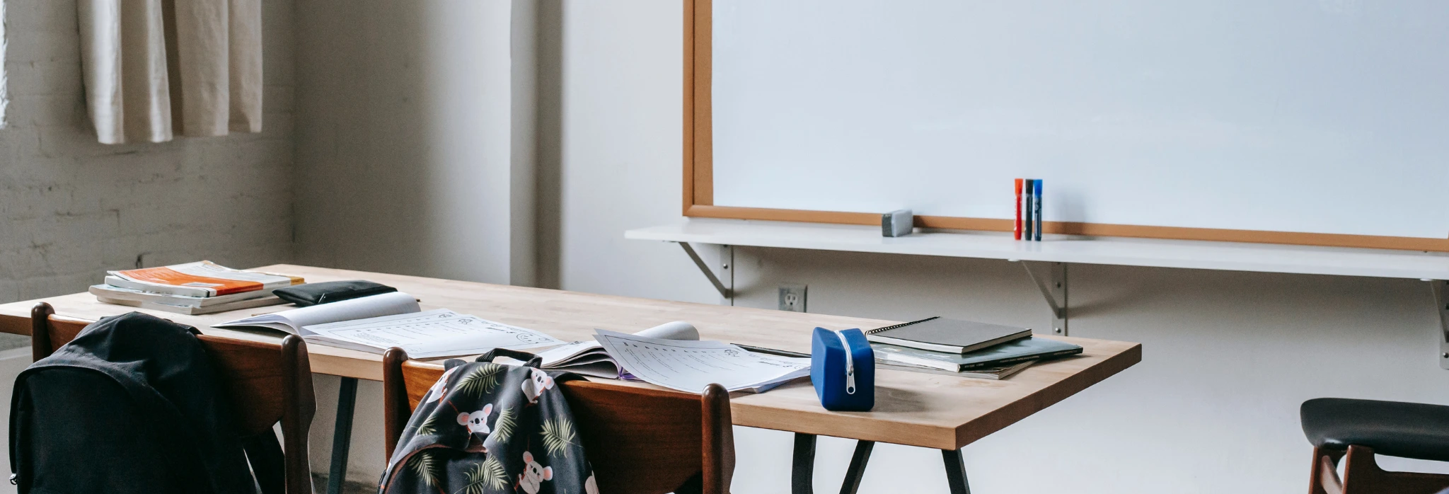 Αίθουσα σχολείου με πίνακα, θρανίο και σχολικά είδη.