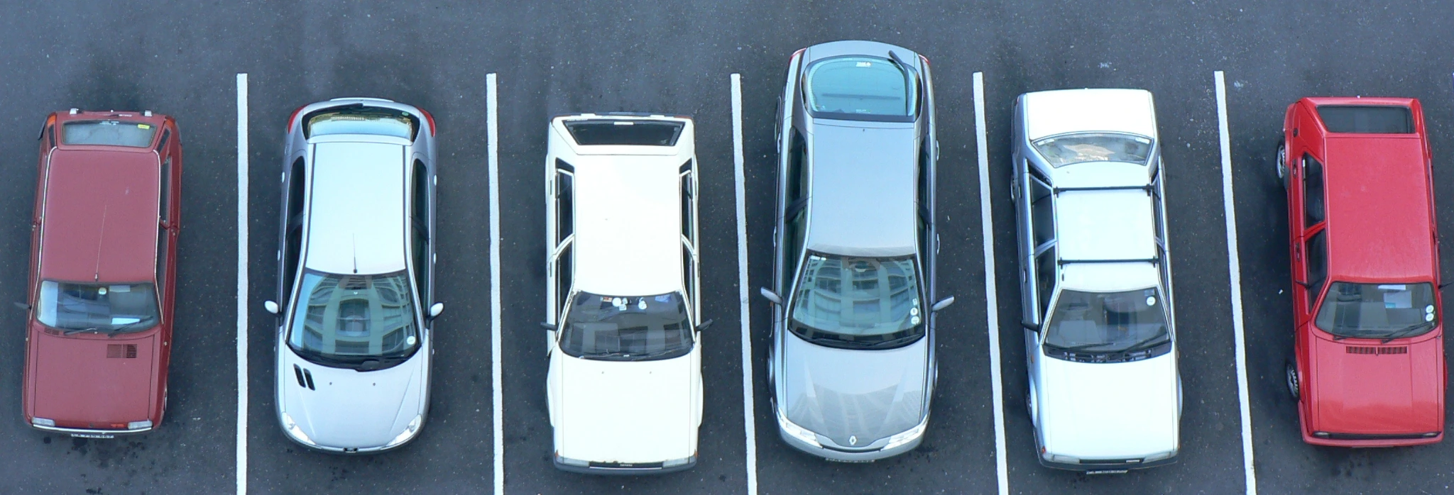 6 σταθμευμένα αυτοκίνητα σε υπαίθριο πάρκινγκ.