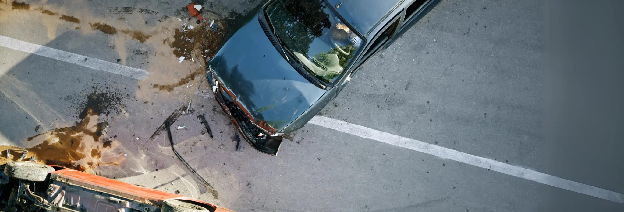 Σύγκρουση δύο οχημάτων σε δρόμο με εμφανείς ζημιές και διαρροή υγρών στο οδόστρωμα.