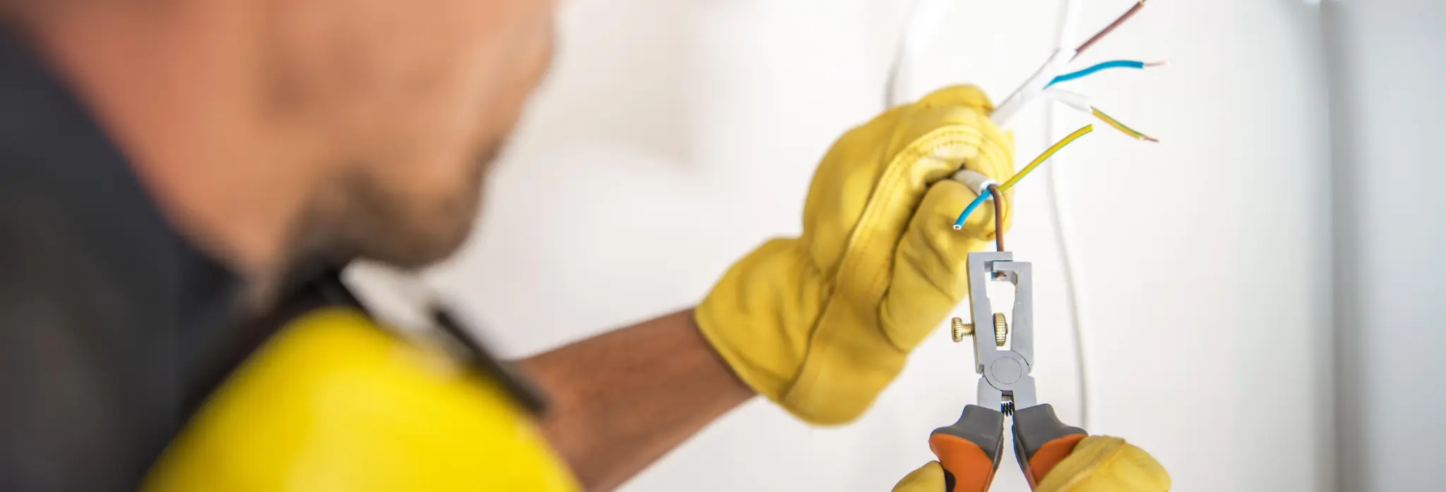 Ηλεκτρολόγος με γάντια ασφαλείας κάνει εργασίες σε καλώδια.