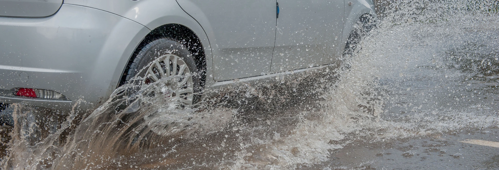 Αυτοκίνητο διασχύει πλημμυρισμένο δρόμο.
