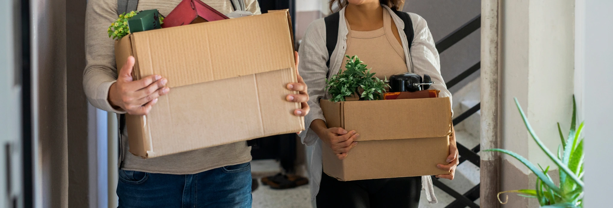 Δύο άτομα μεταφέρουν κούτες με πράγματα σε διαμέρισμα.