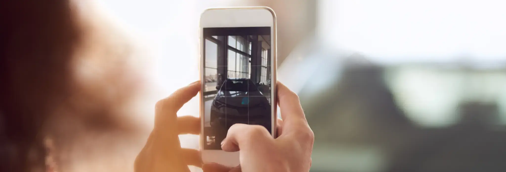 Χέρια κρατάνε κινητό και φωτογραφίζουν αυτοκίνητο.