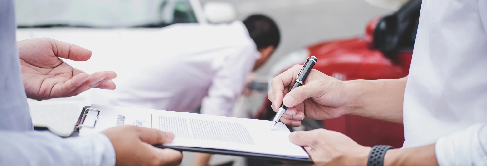 Άνθρωπος υπογράφει χαρτιά μπροστά από αυτοκίνητο